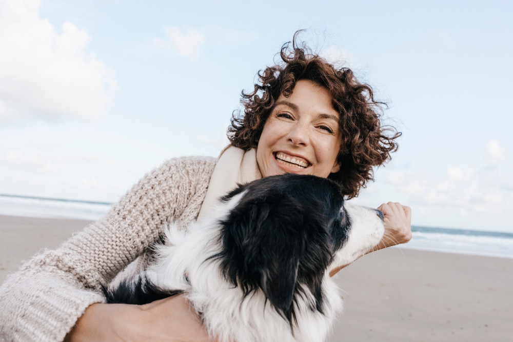 Happy woman with dog on the beach after overcoming benzodiazepine addiction